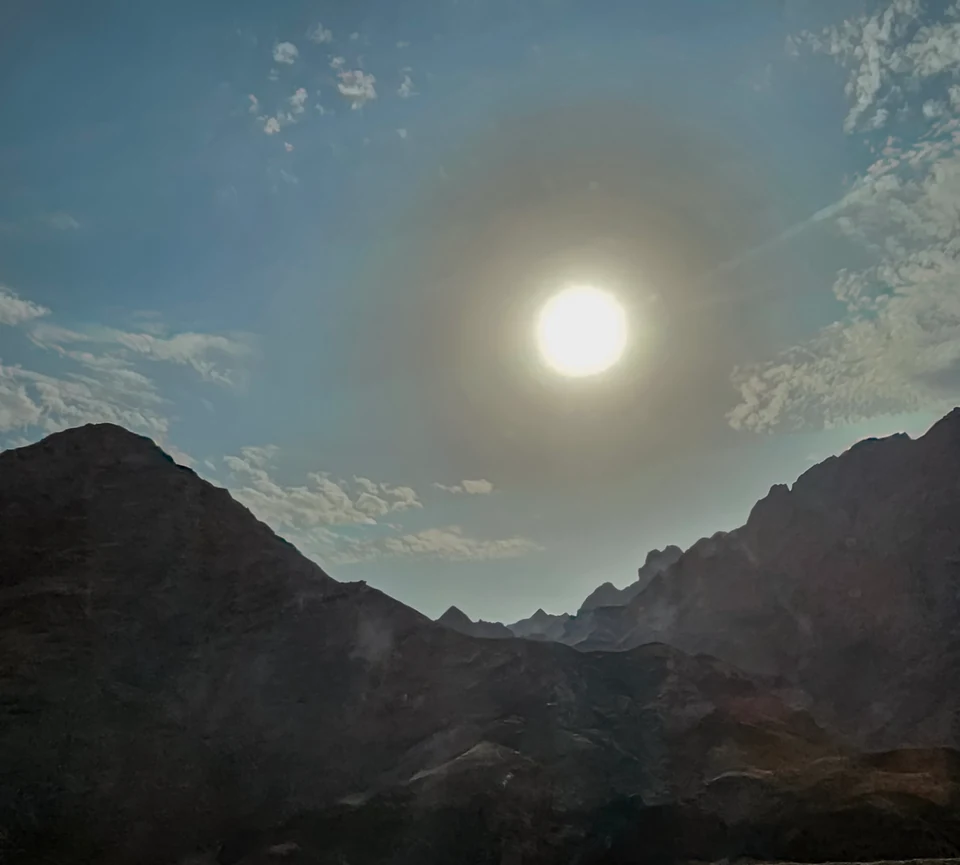 The bright sun above a rugged mountain ridge in South Sinai, framed by scattered clouds